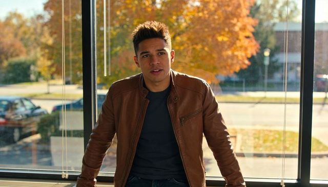 Young man leaning on window analyzing urban traffic data with autumn light