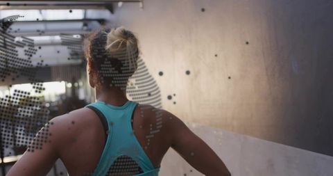 Athletic woman standing hands on hips in narrow corridor wearing teal racerback top