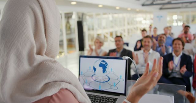 Businesswoman in headscarf presenting to diverse team with network concept on laptop - Download Free Stock Images Pikwizard.com