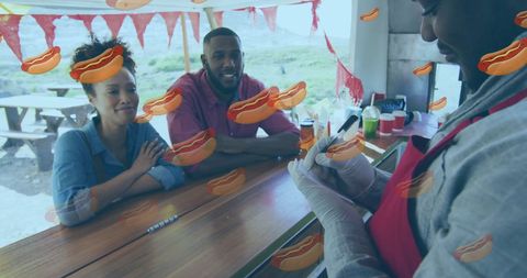 Couple ordering at outdoor hot dog stand during street food fair