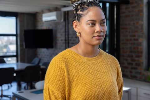 Businesswoman in mustard sweater contemplating in modern office