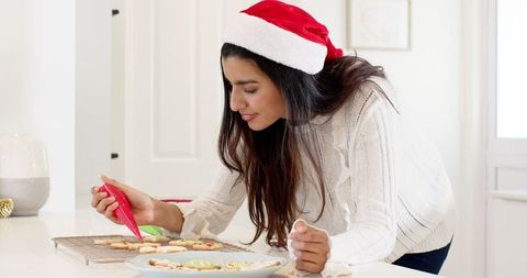 Woman Icing Christmas Cookies in Festive Home Kitchen
