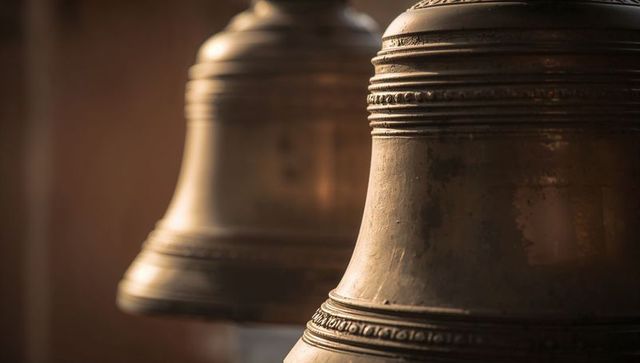 Antique bronze bell close-up showing worn patina and ornate concentric bands in bell tower