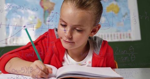 Young student enthusiastically writing in classroom