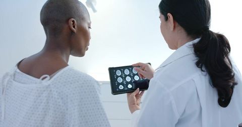 Doctor reviewing brain MRI on tablet with Black female patient in clinic consultation