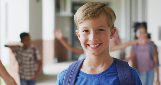 Smiling schoolboy stands in school hallway wearing backpack, ready for class. Ideal for educational campaigns, back-to-school promotions, and materials promoting positive school environments.
