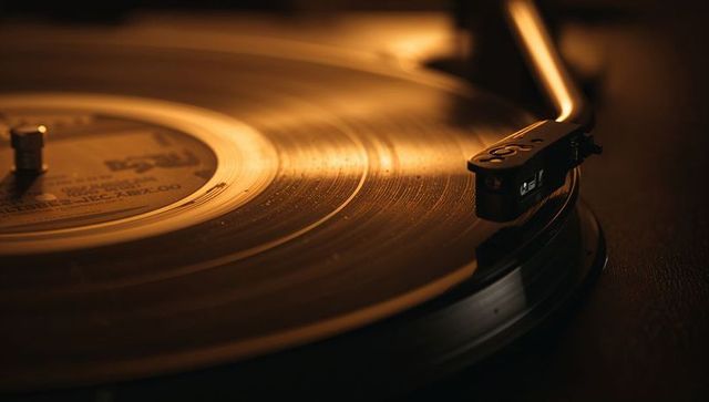 Warm vintage vinyl turntable tonearm tracing grooves in golden ambient light