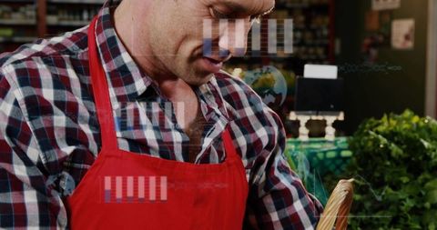 Local market vendor wearing red apron tending wicker basket of fresh market greens