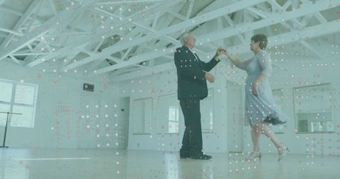 Elegant senior couple dancing in spacious studio interior