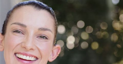 Mid adult woman smiling in sunlit garden with gold earring