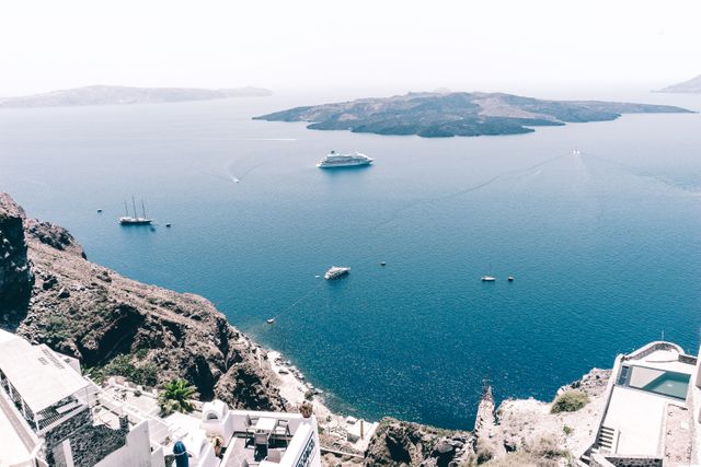 Perfect for travel brochures, vacation planning, Mediterranean tourism promotions, and websites related to Greek islands. Highlights the beauty of Santorini caldera with boats and a cruise ship, conveying a relaxing and scenic holiday destination.