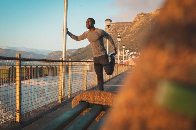 African American man stretching on a pier at sunset, preparing for a run. Ideal for promoting healthy outdoor lifestyles, fitness training programs, and athletic wear. Suitable for use in fitness blogs, health magazines, and advertisements for sports equipment.