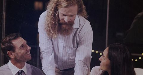 Bearded businessman leading discussion on illuminated rooftop terrace