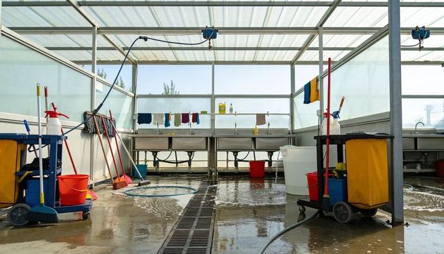 Commercial wash bay with janitorial carts, mops and wet concrete for industrial cleaning