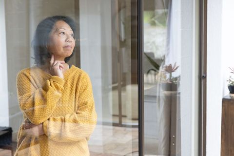 Pensive Senior Woman by Glass Door in Modern Home Interiors