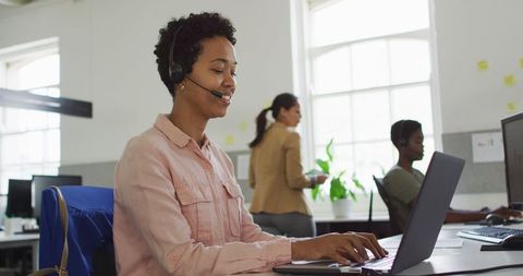 Smiling businesswoman using headset at office desk
