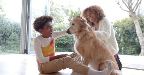 Smiling Mother and Son Enjoying Time with Golden Retriever at Home