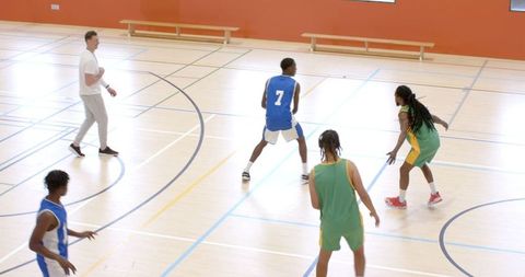 Diverse basketball team practicing defensive drills on hardwood court