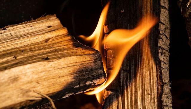 Crackling split firewood logs glowing with orange-yellow flame and charred bark in hearth