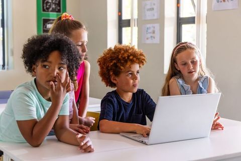 Multiracial Children Collaborating on Classroom Laptop Project for Group Learning