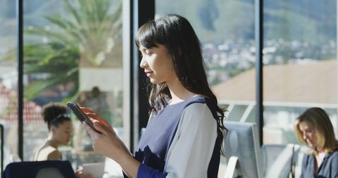 Businesswoman using tablet in sunlit modern office