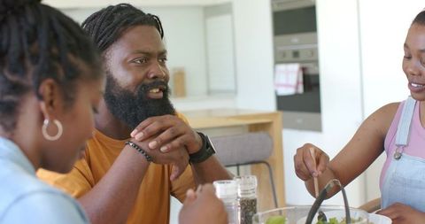 Family sharing healthy salad and conversation at modern sunlit kitchen table