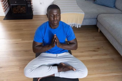 Man meditation cross-legged on yoga mat at home