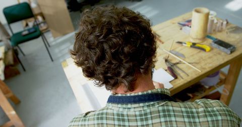Focused artisan engaging in fine craftwork at workshop table