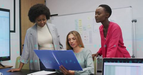 Women Collaborative Examining Binder for Business Strategy Meeting