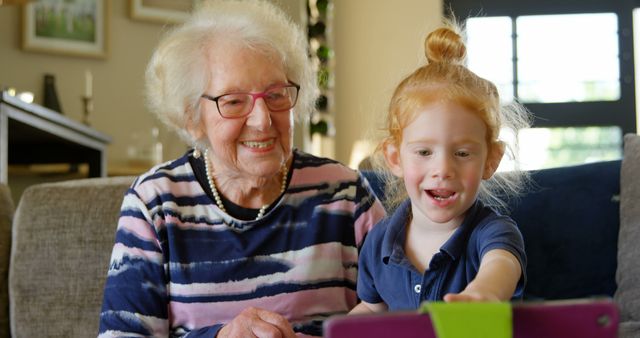 Grandmother with Granddaughter Using Tablet at Home, Both Amused and Smiling - Download Free Stock Images Pikwizard.com