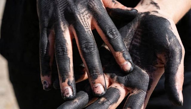 Hands showing black ink stains and text transfer, close-up of stained nails and texture