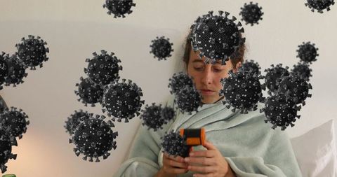 Sick woman using thermometer with virus overlay illustrating illness