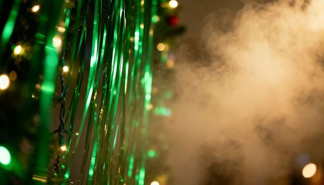 Green metallic streamers and warm light haze creating festive bokeh and shimmering glow