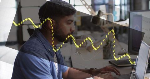 Man coding and analyzing data on laptop in open-plan office with digital analytics overlay