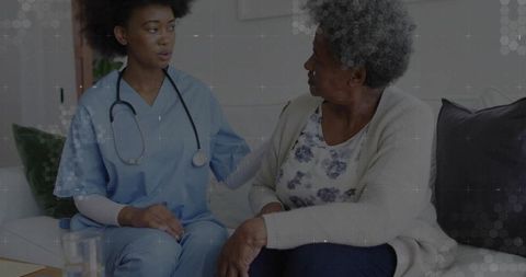 African american nurse comforting senior woman in home setting