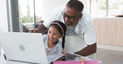 Grandfather Teaching Granddaughter on Laptop at Home