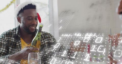 Man pouring white wine at festive holiday dinner wearing santa hat with digital overlay