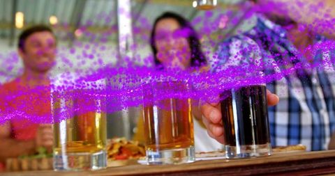 Friends reaching for craft beers on bar counter with vibrant purple paint splash