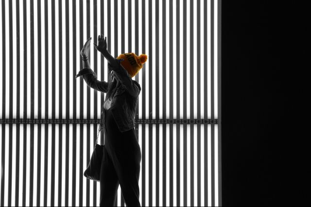 Silhouetted woman wearing yellow hat dancing in urban setting - Download Free Stock Images Pikwizard.com