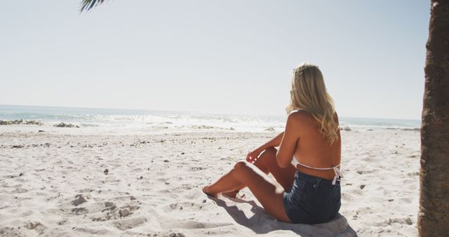 Happy caucasian woman sitting on beach and looking at sea - Download Free Stock Photos Pikwizard.com