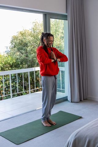 Young african american man practicing morning meditation and yoga at home balcony