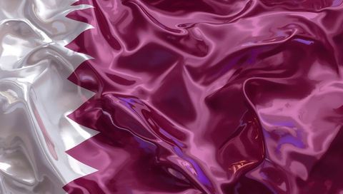 Glossy qatar flag fabric close-up showing maroon field and white serrated nine-point band