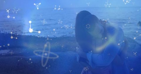 Hugging couple on rocky shoreline with cosmic constellation overlays, dreamy blue romance