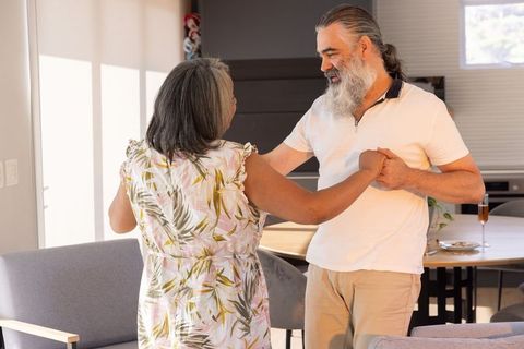 Senior couple sharing tender slow dance in sunlit modern home