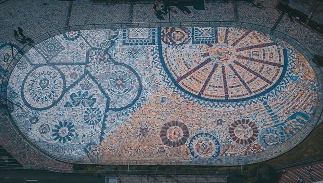 Aerial oval mosaic plaza geometric tessellation with circular floral motifs and urban tile art