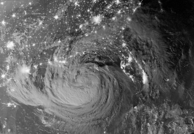 The nighttime satellite view captured by NASA's Suomi-NPP satellite using the VIIRS instrument showcases Tropical Storm Isaac and the surrounding Gulf Coast cities in the United States. The image shows the storm clouds illuminated by moonlight just after local midnight. This image is useful for weather analysis, disaster response planning, meteorology studies, and educational resources on storm dynamics.