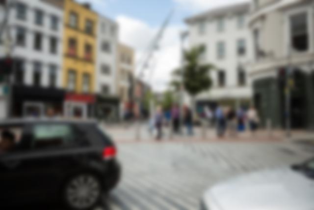Busy urban street scene with blurred buildings and people walking on a sunny day. Suitable for concepts of urban life, motion, and everyday activities in a bustling city environment. Ideal for use in marketing materials, advertisements, and urban lifestyle blogs.