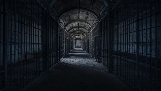 Abandoned Prison Corridor with Metal Bars in Low Light
