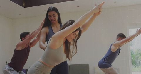 Fitness class with instructor adjusting form in modern home setting