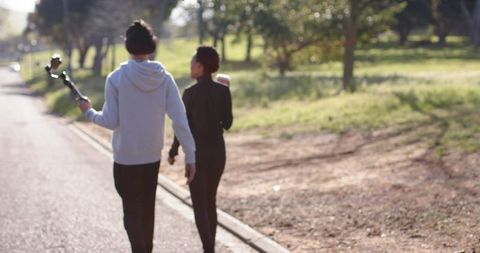 Couple walking in park holding handheld gimbal filming casual outdoor video content